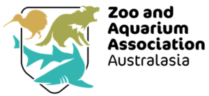 Shield outline encompassing silhouettes of Tasmanian Devil, shark and Kiwi with black text that says 'Zoo and Aquarium Association Australasia'