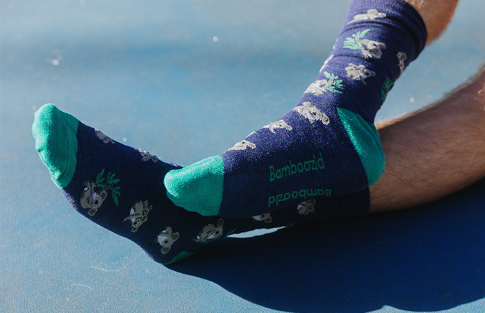 Navy blue crew socks featuring a koala print and green sock and heel patches