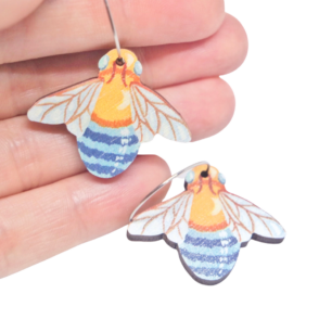 Blue banded bee wooden earrings resting on woman's hand