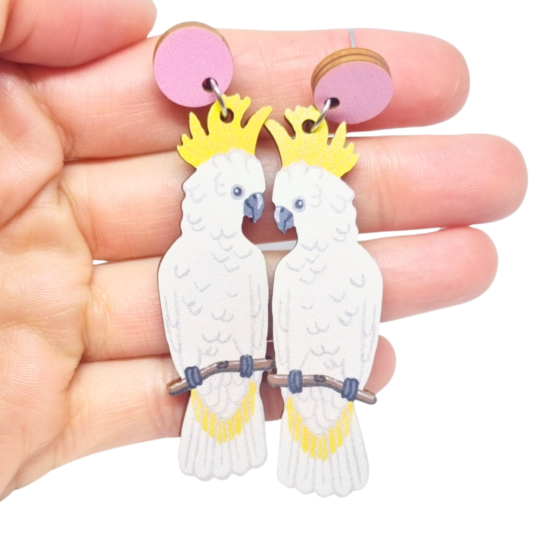 Cockatoo wooden earrings resting on woman's hand