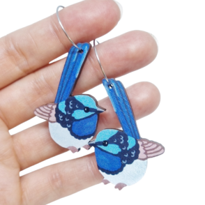 Blue wren wooden earrings resting on woman's hand