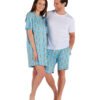 Woman and man standing together. Man has arm around woman and both are smiling. Woman wears a light blue sleep dress with meerkat print and man wears a white tshirt and light blue shorts with meerkat print