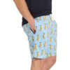 Man standing side on with hands in pockets wearing a black tshirt and blue sleep shorts featuring an all-over meerkat print