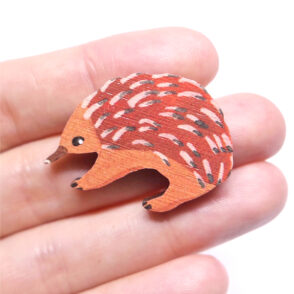 Echidna wooden brooch resting on woman's hand