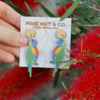 Woman holding piece of cardboard with Rainbow Lorikeet wooden earrings resting on them. Text reads "Pixie Nut & Co"
