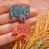 Wombat and echidna wooden brooch resting on woman's hand