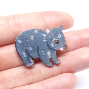 Wombat wooden brooch resting on woman's hand