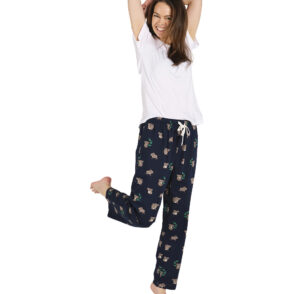 Woman standing with arms above her head and one knee bent up. Woman wears a white tshirt and navy blue pants with koala print